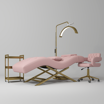 Pink massage table with gold frame and chair on a gray background