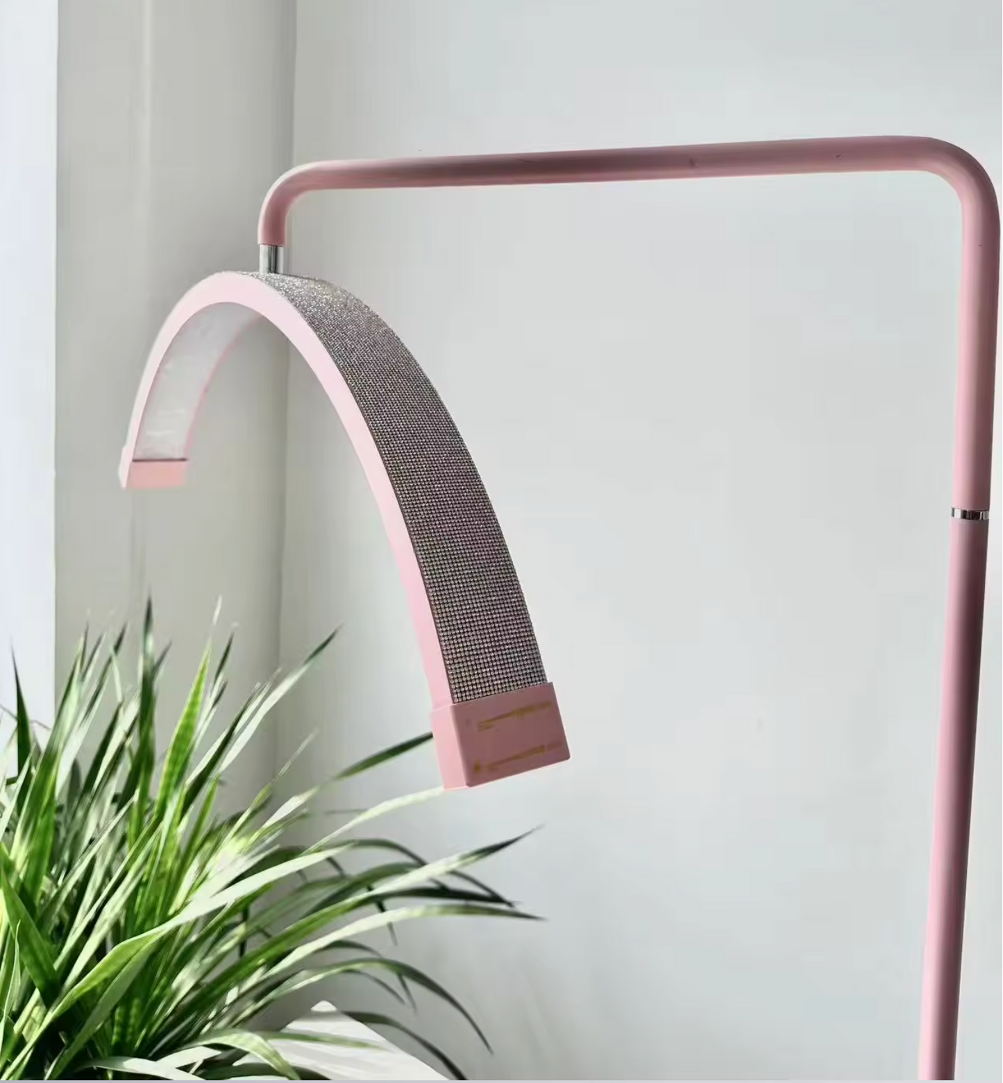 A pink floor lamp with a flexible neck, standing in a relaxed S shape, with a sturdy base. It has a switch on the stem and is connected to a power cord.