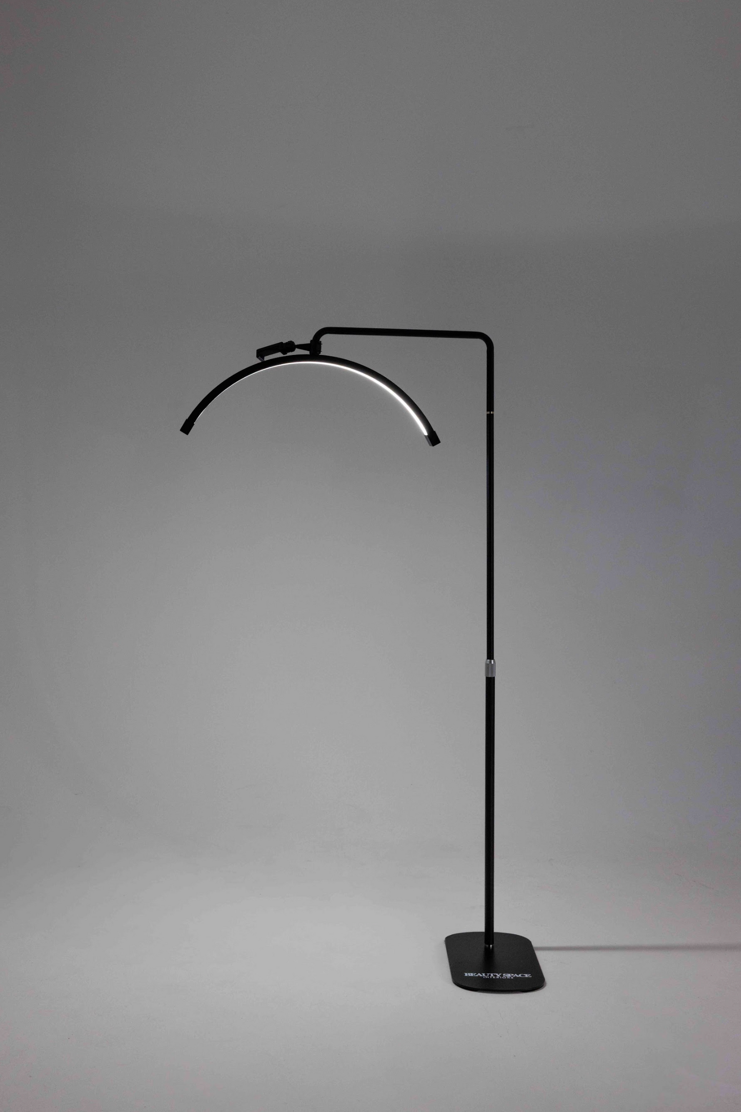 A black floor lamp with a flexible neck, standing in a relaxed S shape, with a smaller loop at the top and a solid base.